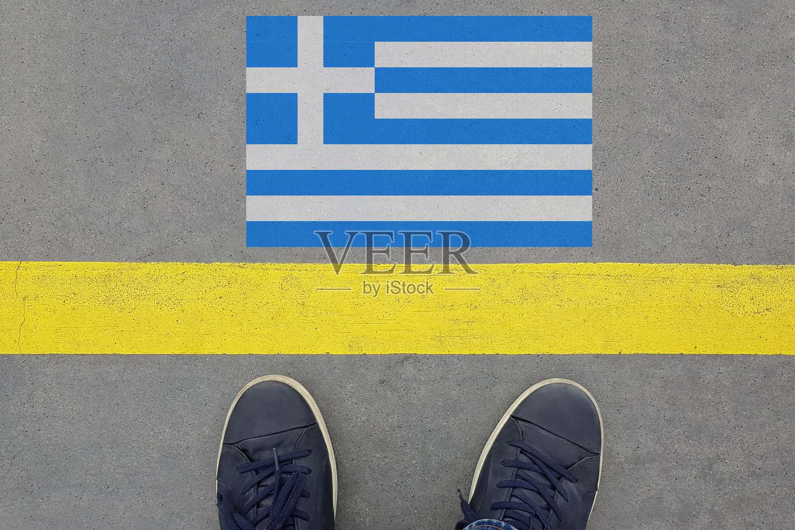 从带着希腊国旗和穿着鞋子的腿的柏油路开始。移民和旅游在希腊的概念照片摄影图片