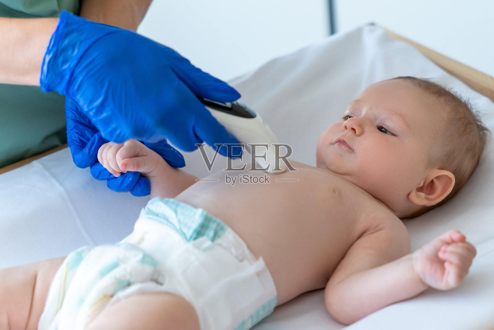 医生的手拿着体温计在婴儿的身体和测量他的体温照片摄影图片