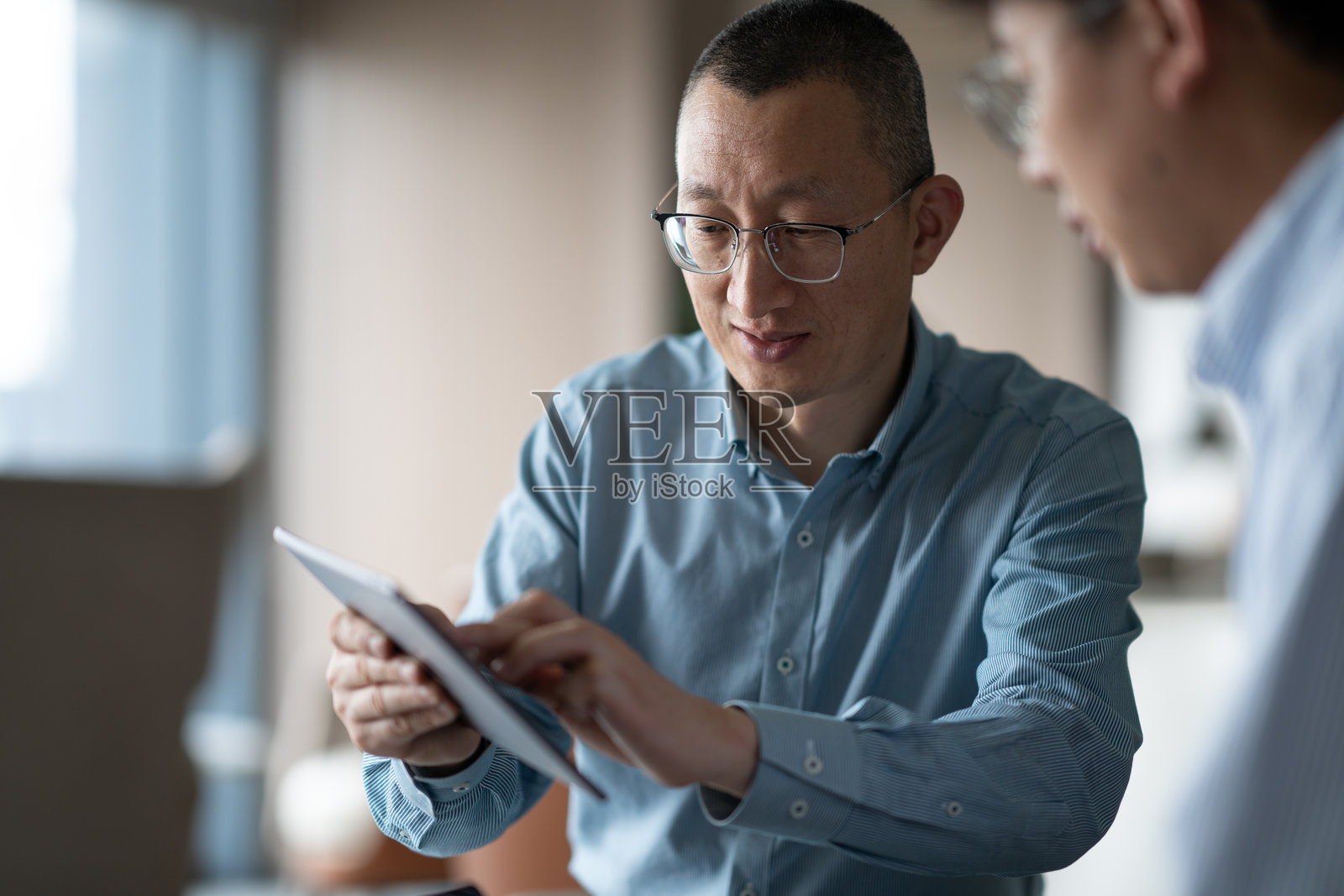 商务人士在办公场所使用平板电脑洽谈业务照片摄影图片