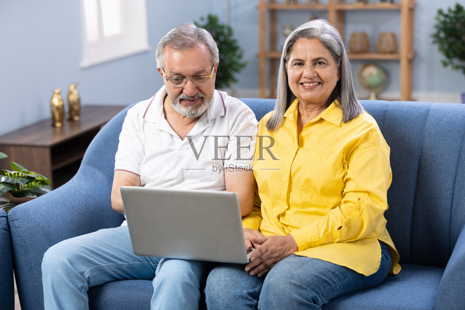 老夫妇坐在家里的沙发上使用笔记本电脑照片摄影图片