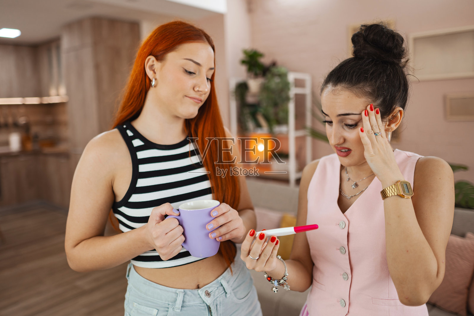 在一个阳光明媚的下午,两名年轻女子在一间时髦的公寓里喝着咖啡,得知验孕结果后分享了一个惊喜照片摄影图片