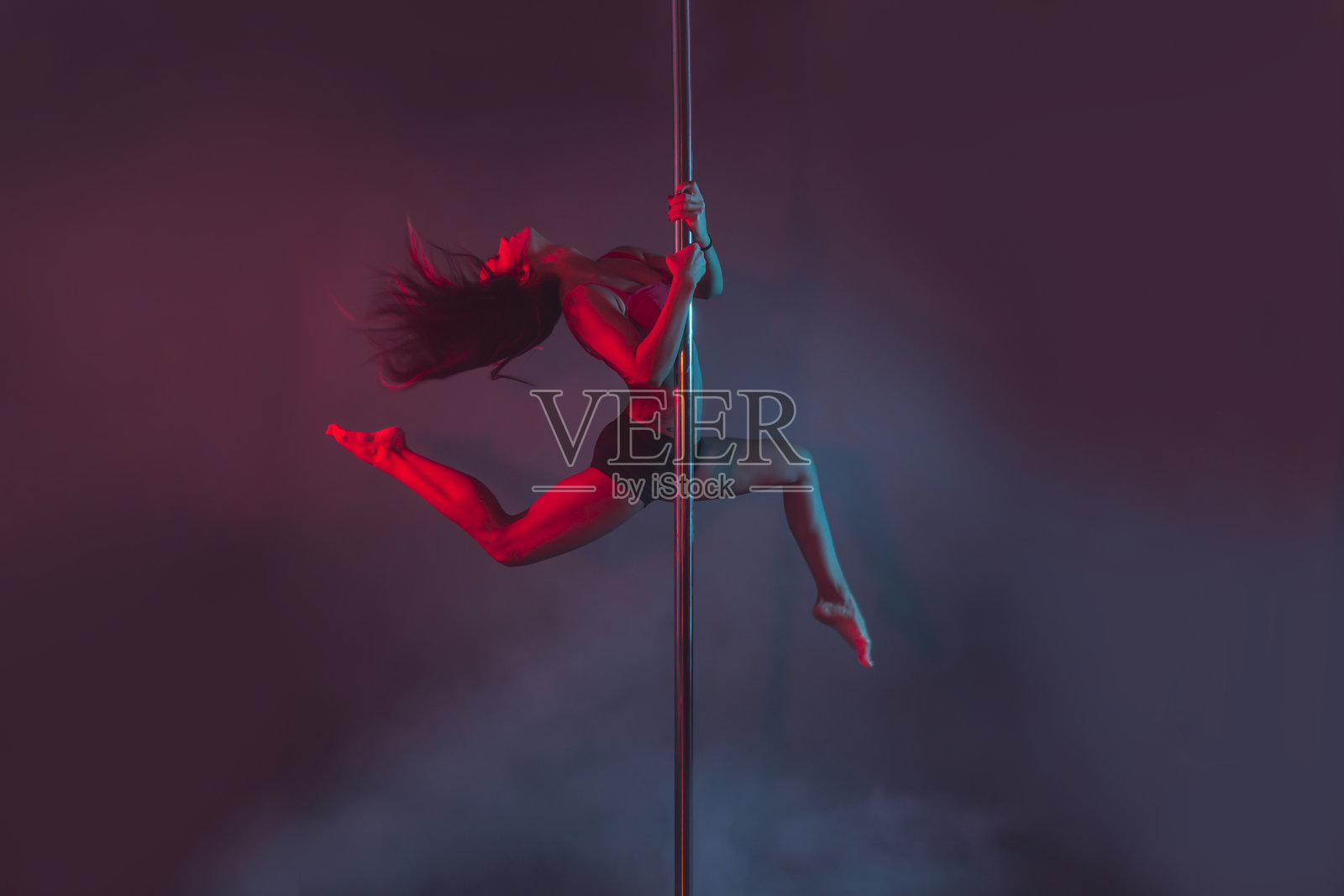 年轻的钢管舞者在有色背景下表演照片摄影图片