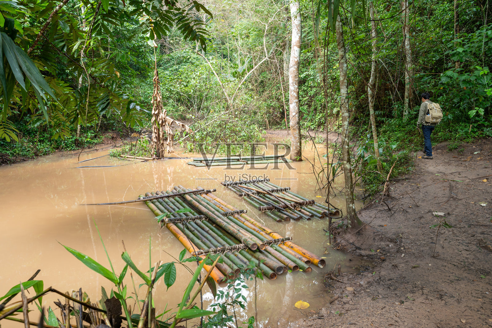 探险者在雨林的河岸上观察竹筏照片摄影图片