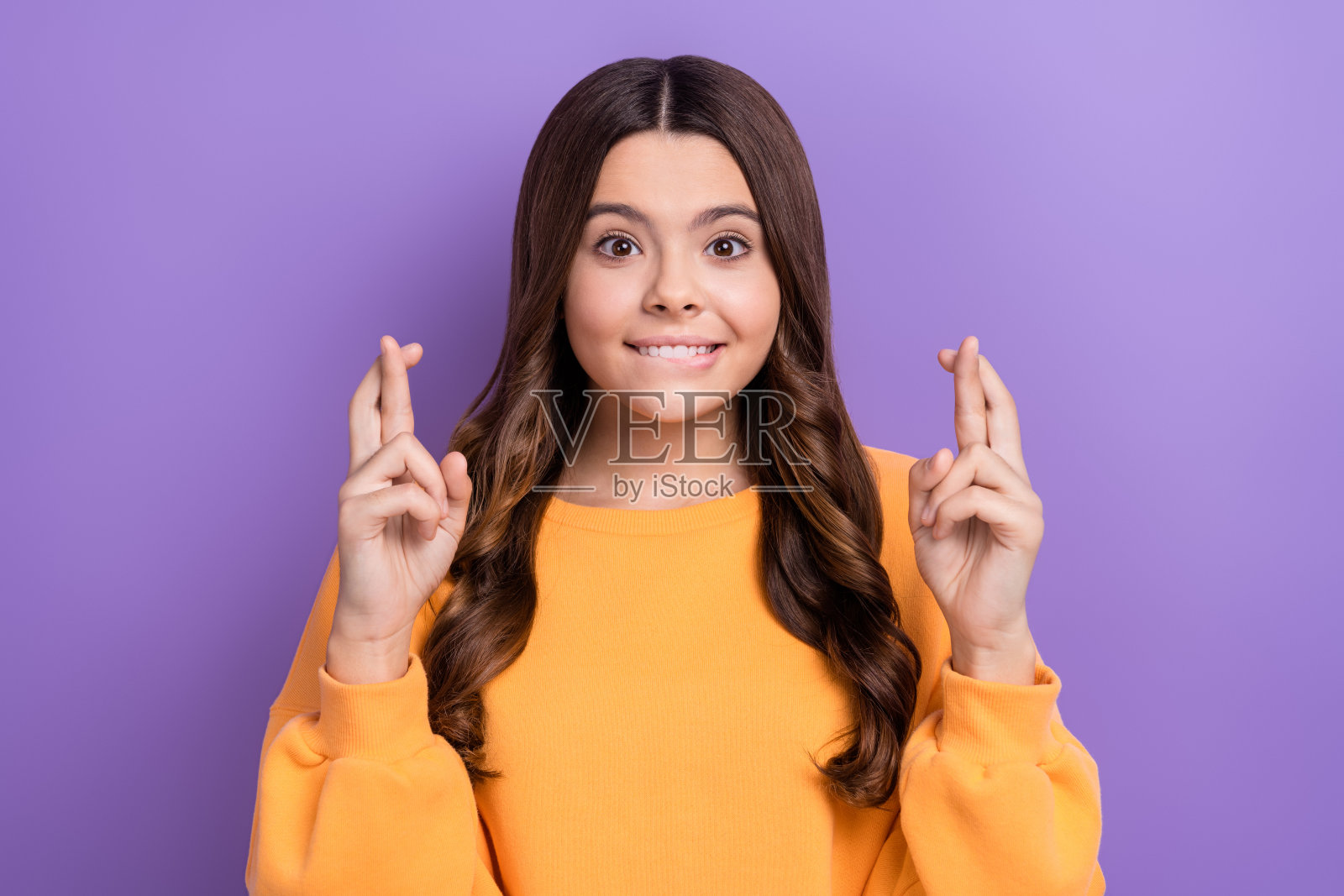 照片中,可爱的兴奋的女士穿着时尚的衣服,交叉着手指,等待着紫色背景的考试结果照片摄影图片