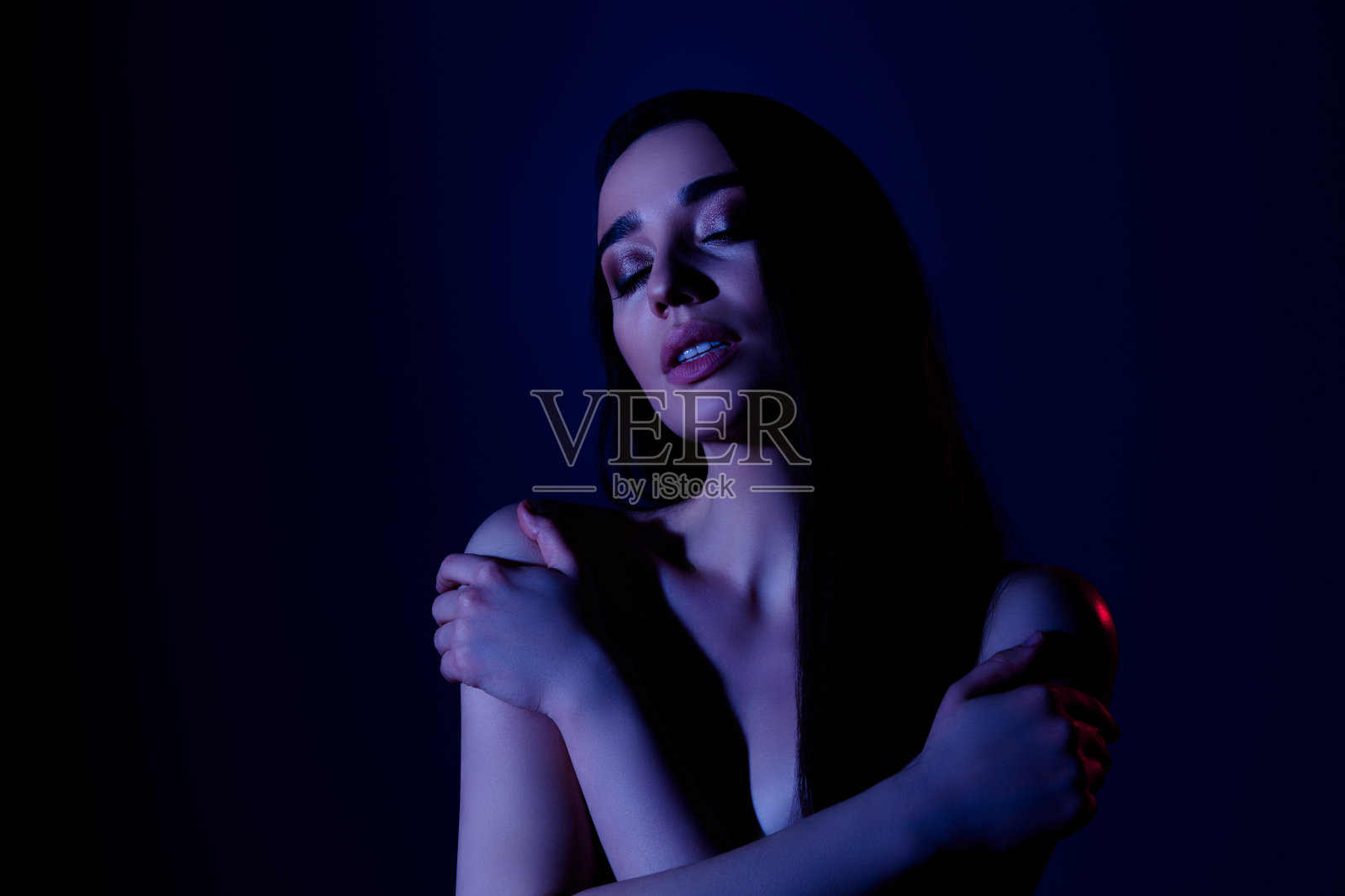 女孩自我拥抱触摸身体的照片感觉新鲜孤立的黑暗霓虹色背景照片摄影图片