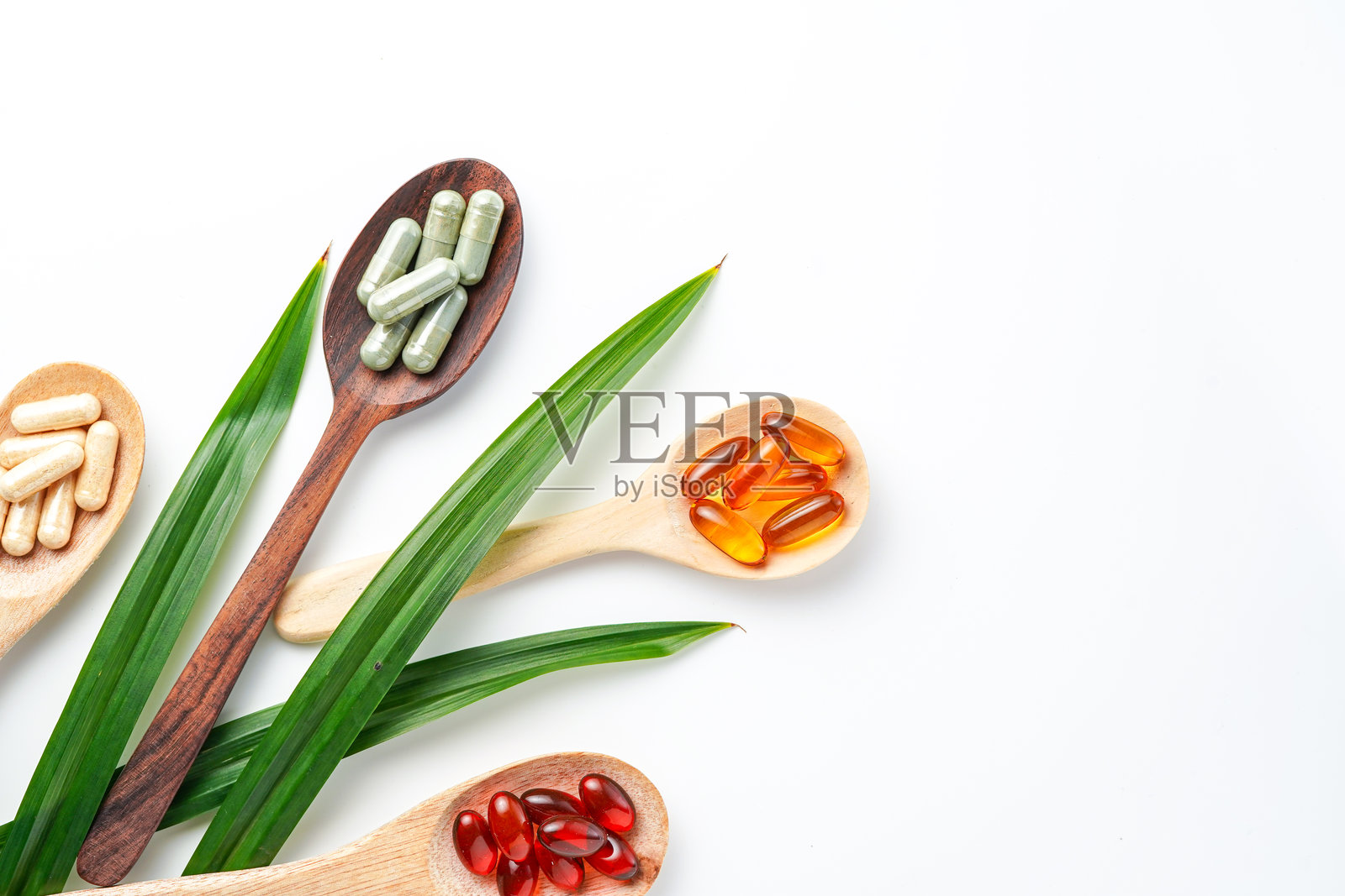 不同的草药丸,维生素和矿物质丸在木勺平放膳食补充剂照片摄影图片