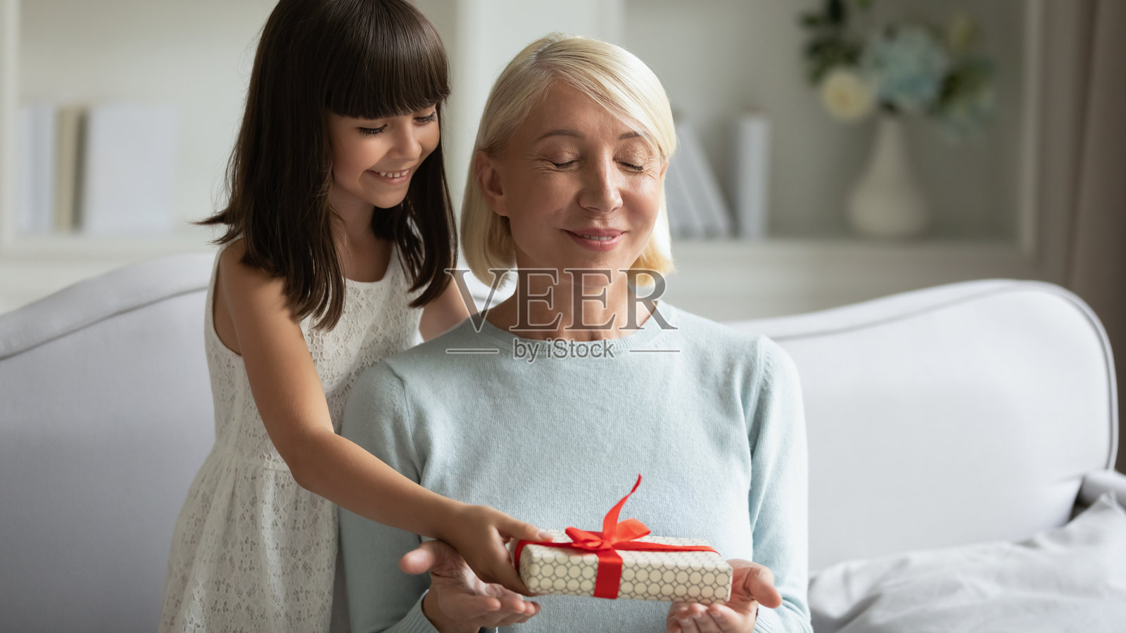 小孙女为微笑成熟的奶奶准备惊喜,赠送礼物照片摄影图片