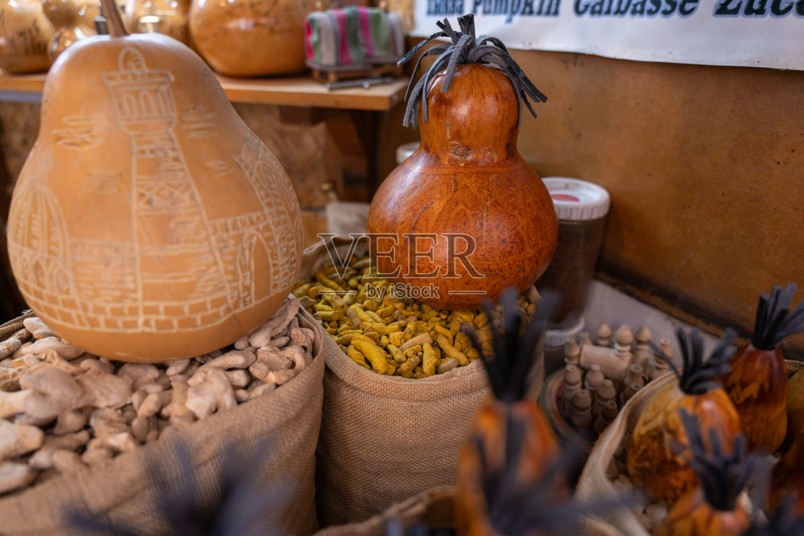 一个黑头南瓜坐在一堆黄色的南瓜上面。南瓜被其他南瓜和南瓜包围,创造了一个丰富多彩的节日展示照片摄影图片