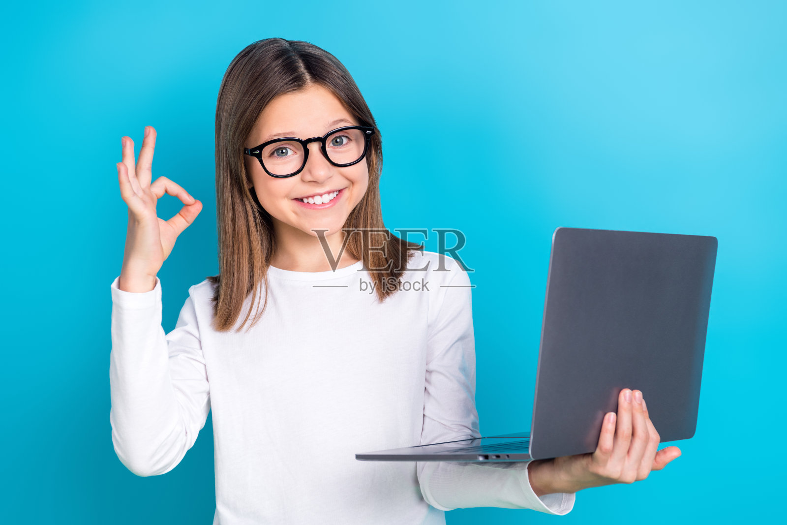 照片中,聪明的女学生梳着直发,穿着白衬衫,手持笔记本电脑,在蓝色背景下显得很孤独照片摄影图片