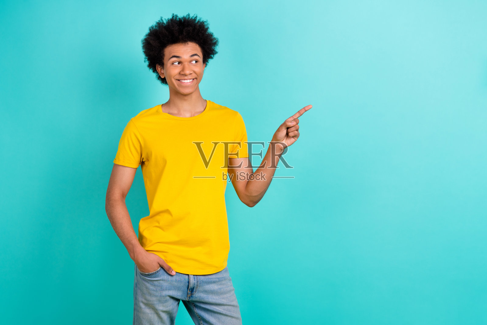 一个穿着黄色t恤的友好开朗的家伙的肖像,在充满活力的蓝绿色背景上看着销售空白的空间照片摄影图片