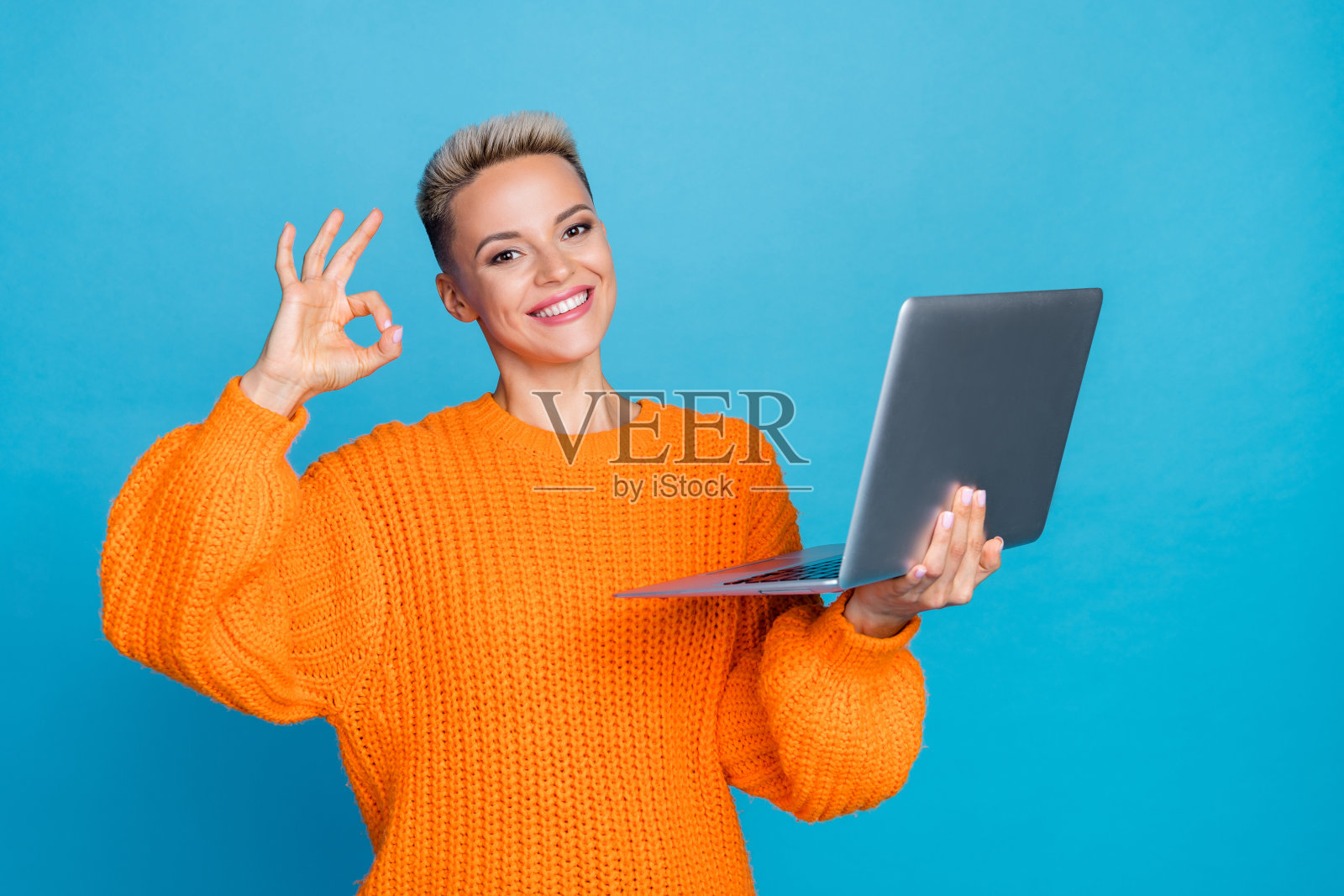 照片中漂亮可爱的女人穿着针织套头衫打字装置,显示空白空间孤立的蓝色背景照片摄影图片