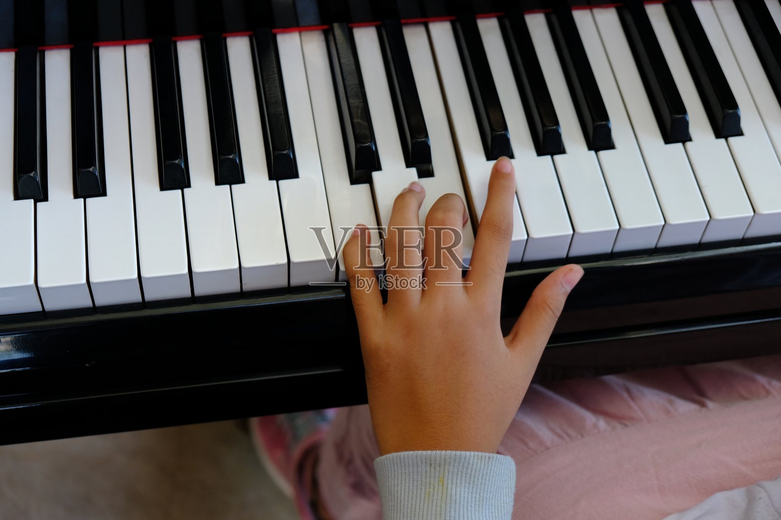 一个女孩的手在按钢琴键,演奏着音乐。照片摄影图片