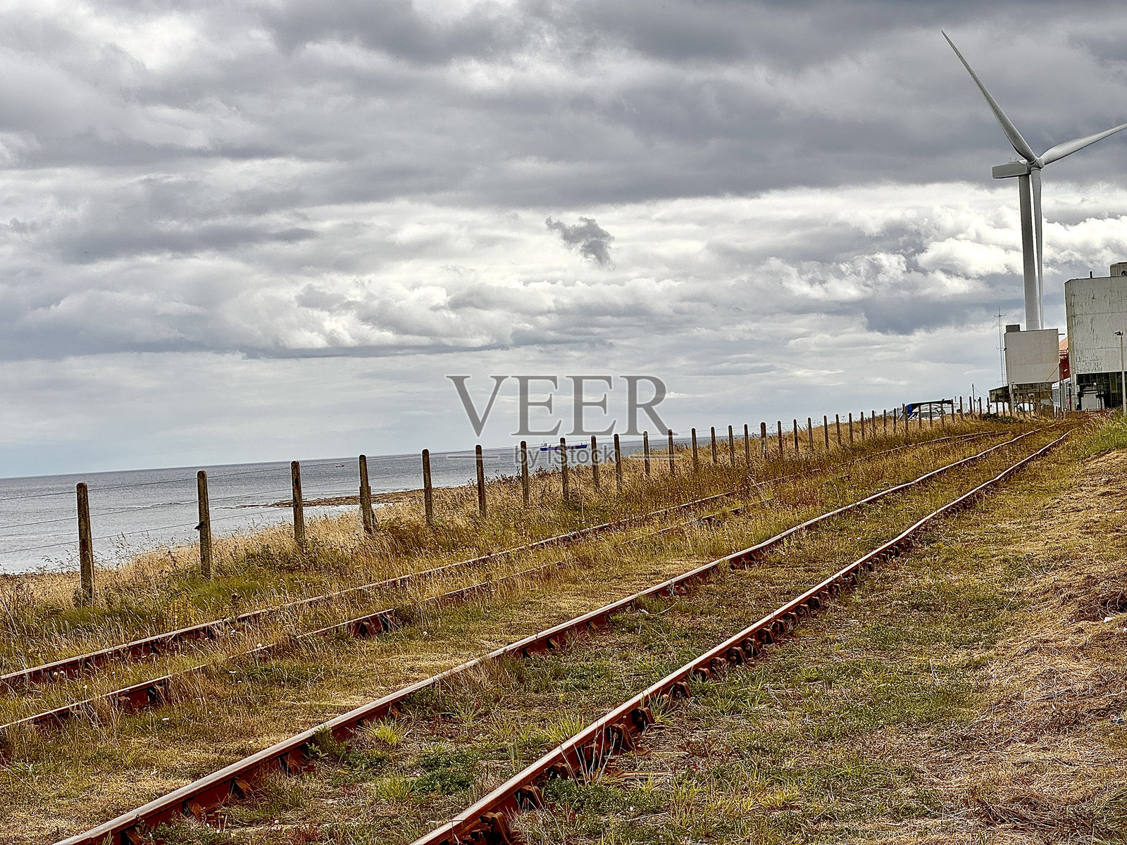 在诺森伯兰郡,一条杂草丛生的废弃铁路,其末端有一个风力涡轮机照片摄影图片