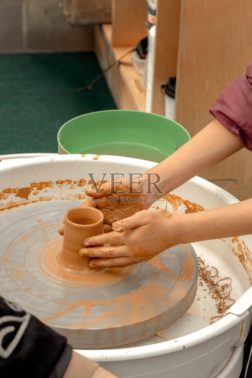 在户外操场上的大师课上,孩子们的手在陶工的转盘上制作陶器照片摄影图片
