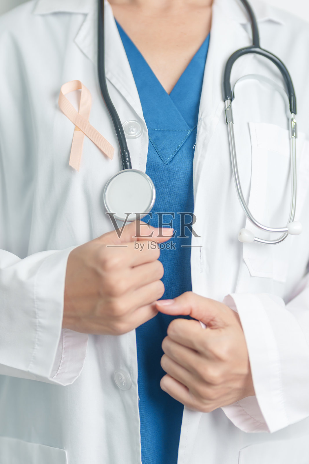 医生手持桃丝带参加九月子宫癌宣传月。子宫和卵巢、子宫内膜异位症、子宫切除术、子宫肌瘤、、保健和世界癌症日的概念照片摄影图片