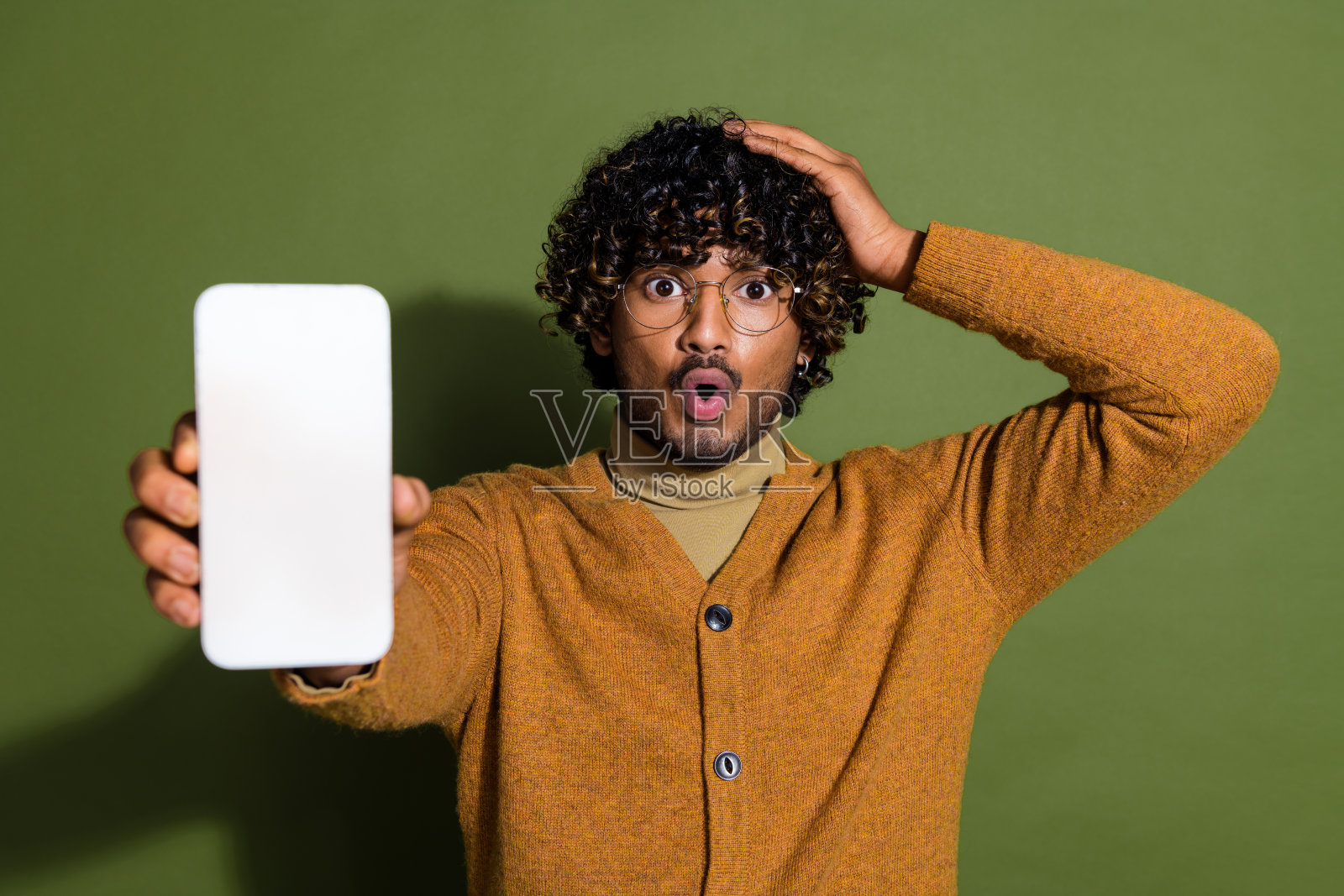 照片中有魅力的年轻人的画像显示装置白色的屏幕吓着穿着时髦的棕色衣服孤立在卡其色的背景照片摄影图片