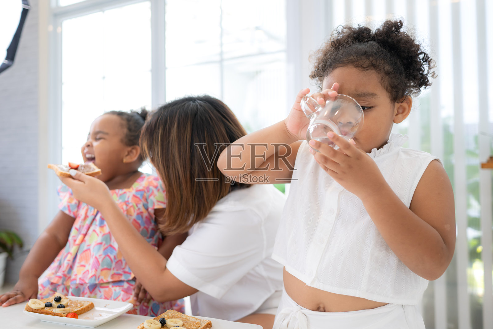 一个假日,一位妇女和她的两个小女儿坐在一户人家的客厅里吃水果照片摄影图片