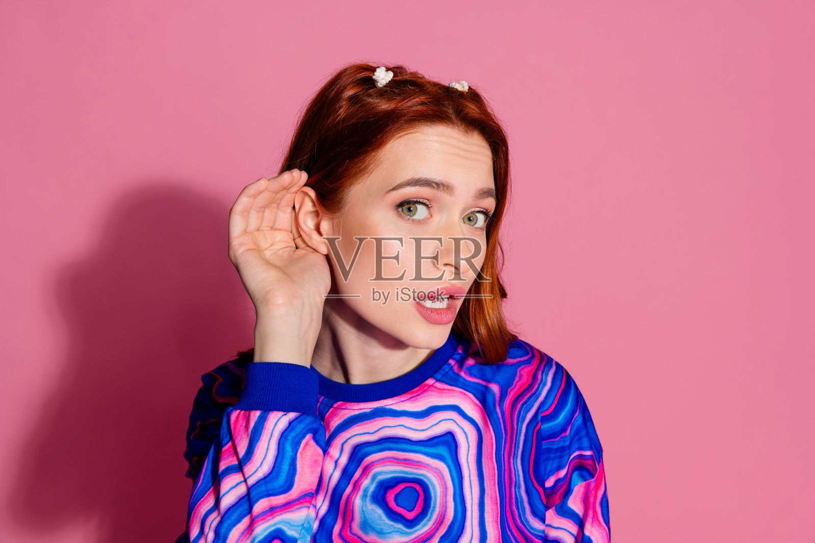 漂亮的年轻女孩的照片肖像听新闻秘密封面耳朵穿时髦的蓝色彩色服装孤立在粉红色的背景照片摄影图片