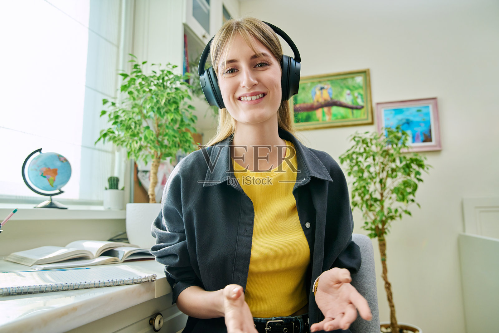 十几岁的女学生戴着耳机在家里开视频会议,用网络摄像头观看照片摄影图片