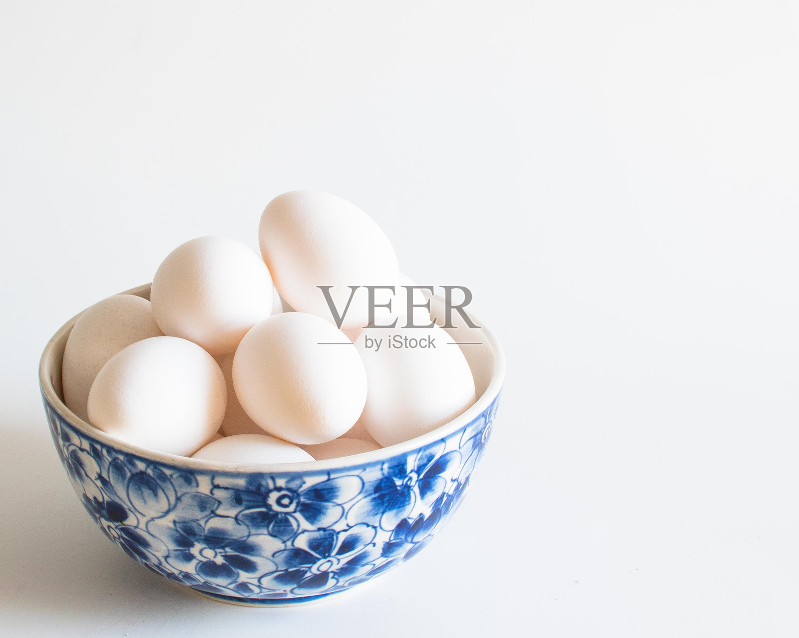 白色背景下碗里的鸡蛋特写照片摄影图片