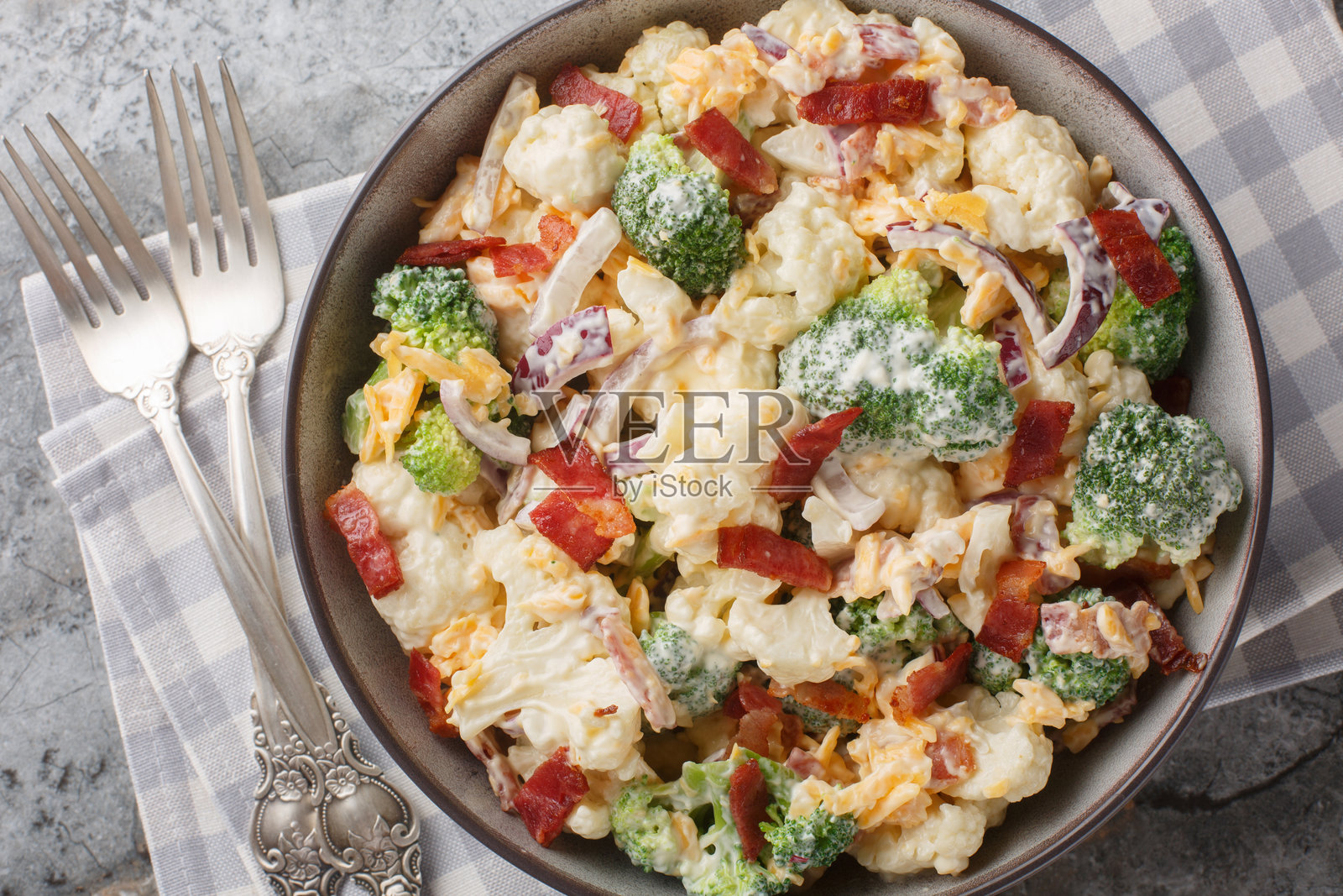 沙拉有花椰菜,西兰花,熟培根,奶酪和红洋葱特写在碗里。水平俯视图照片摄影图片