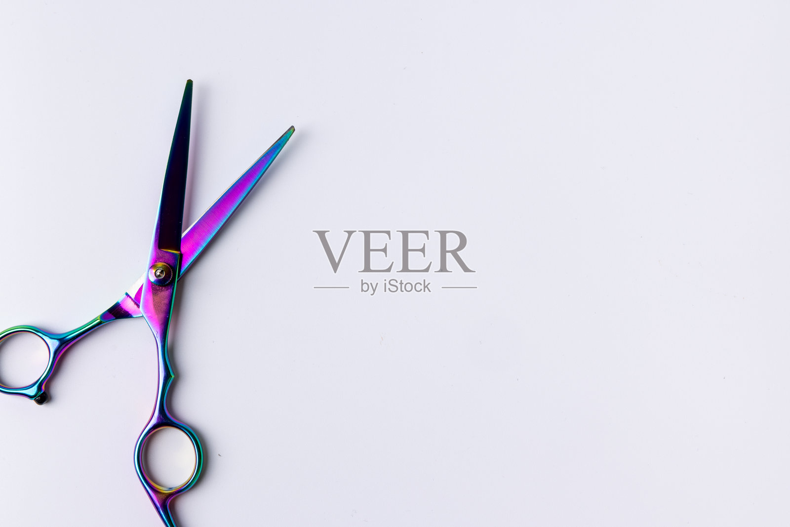 从上方看,白色表面上打开的剪刀的特写。剪刀是向左对齐的照片摄影图片