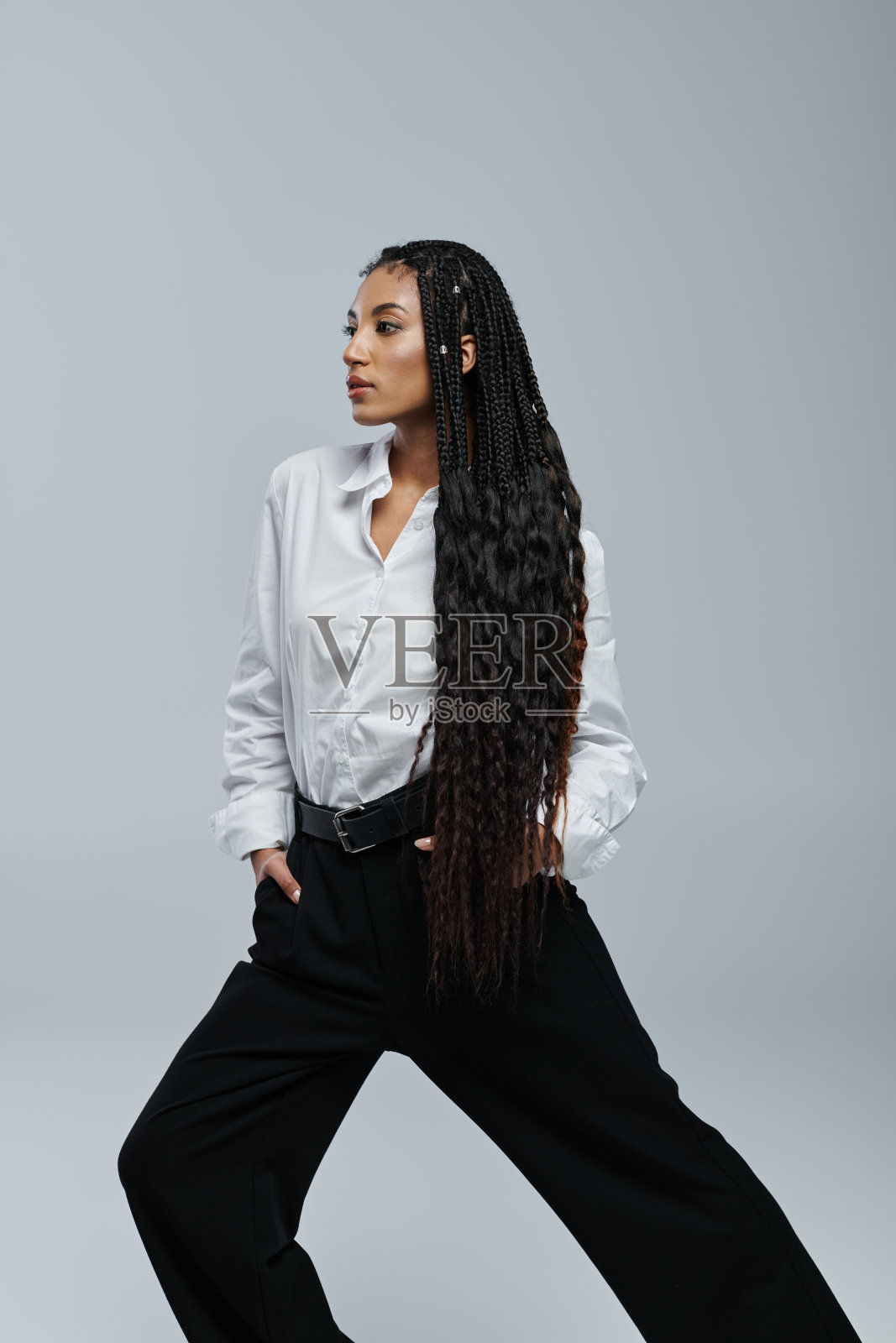 年轻的非裔美国女性梳着辫子,在现代的工作室里展示着时尚的服装照片摄影图片