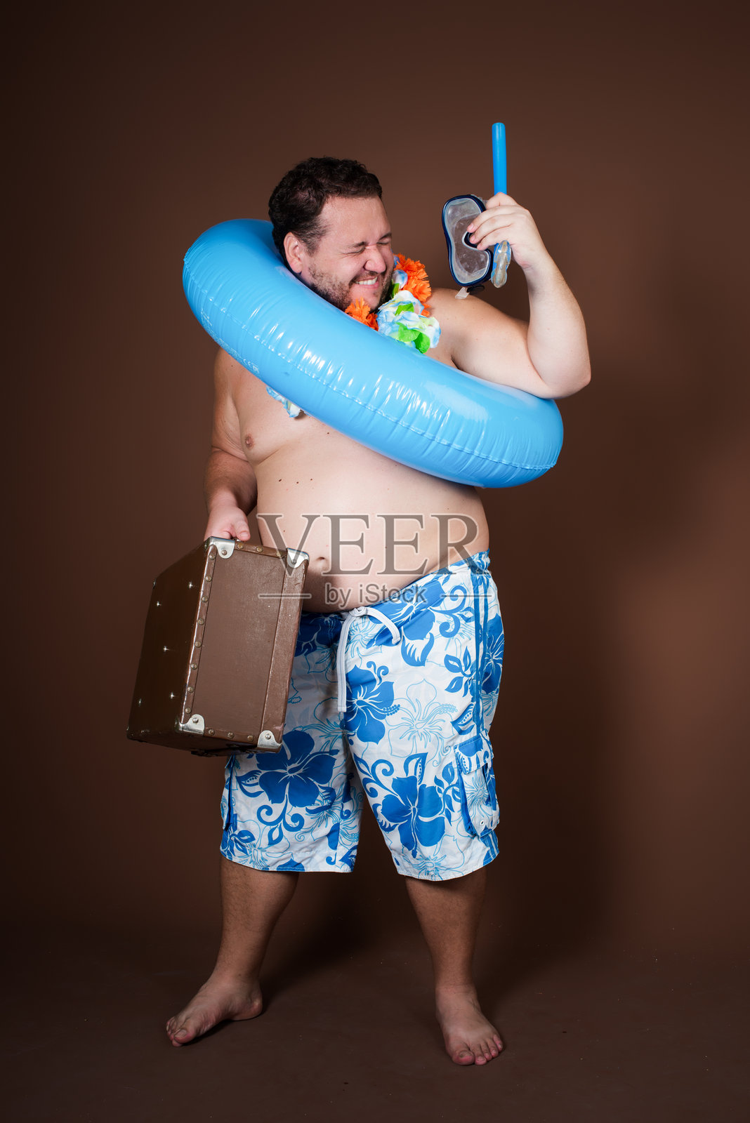 带着充气戒指的滑稽胖子要去度假了。照片摄影图片