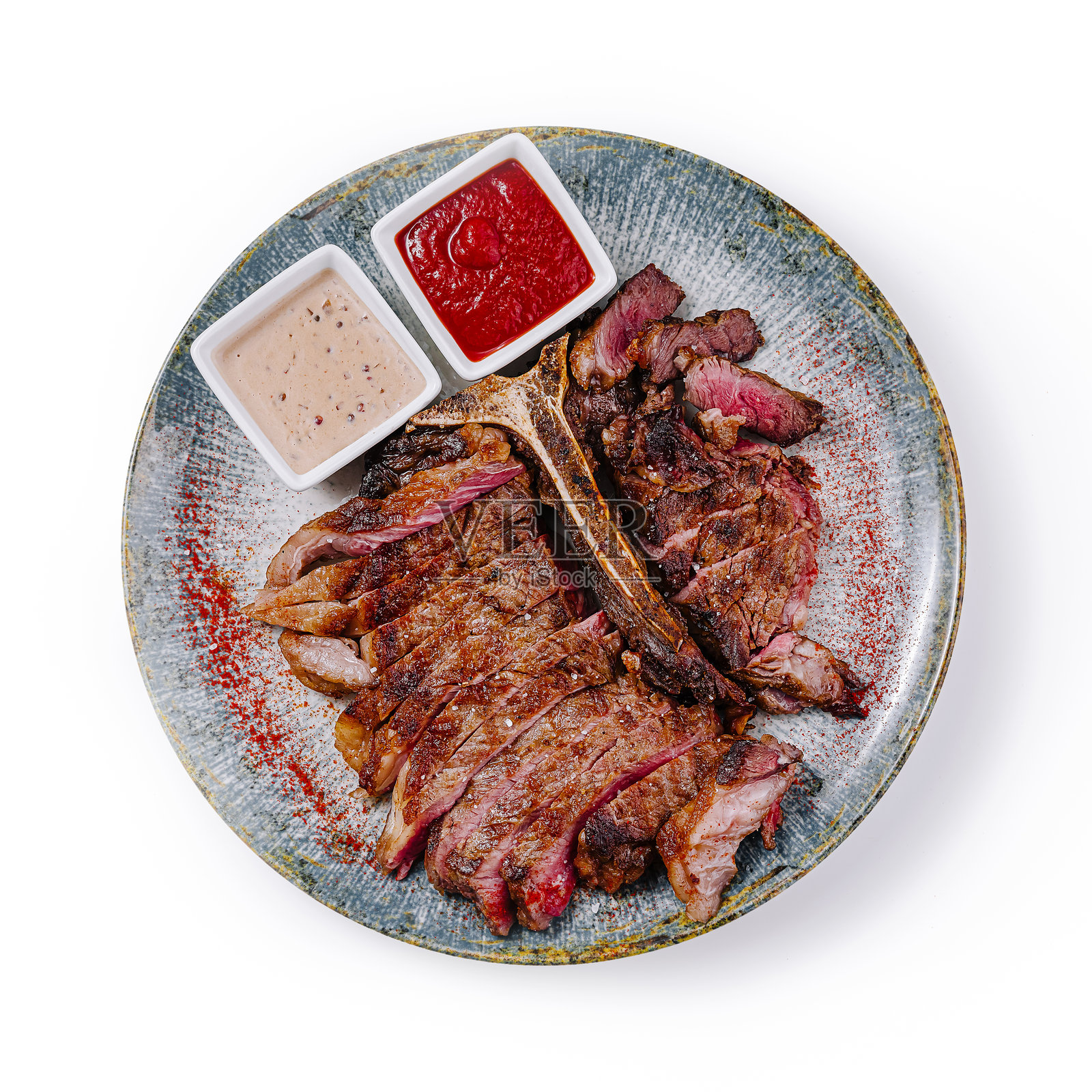 切片烤t骨牛排与酱汁在盘子里,俯视图照片摄影图片