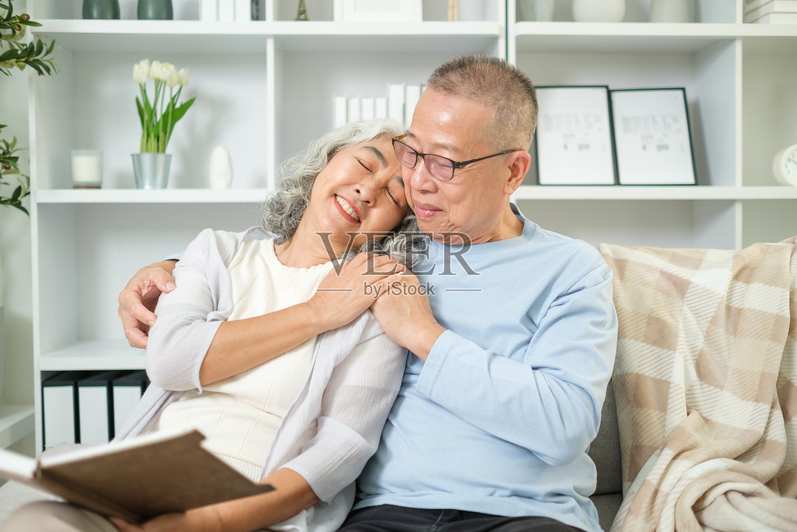 一对老夫妇坐在温暖诱人的客厅里舒适的沙发上。照片摄影图片