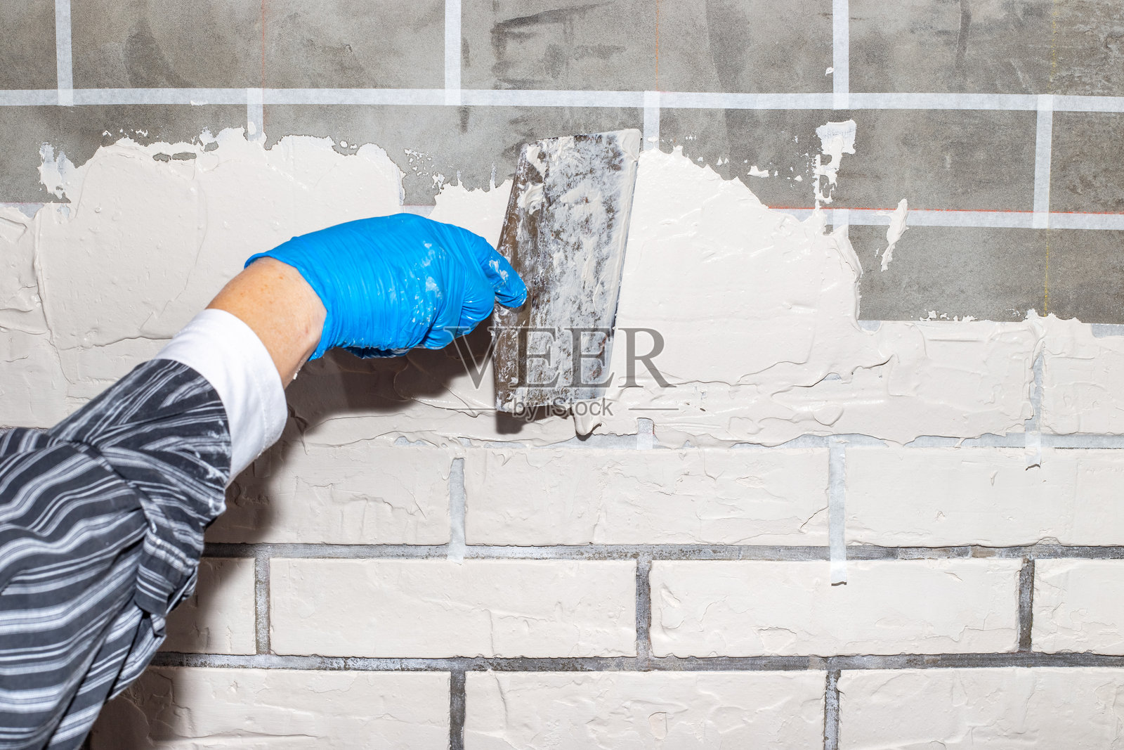 在装饰砖下面用石膏完成墙面。阶段2。用抹刀把灰泥涂在墙上照片摄影图片