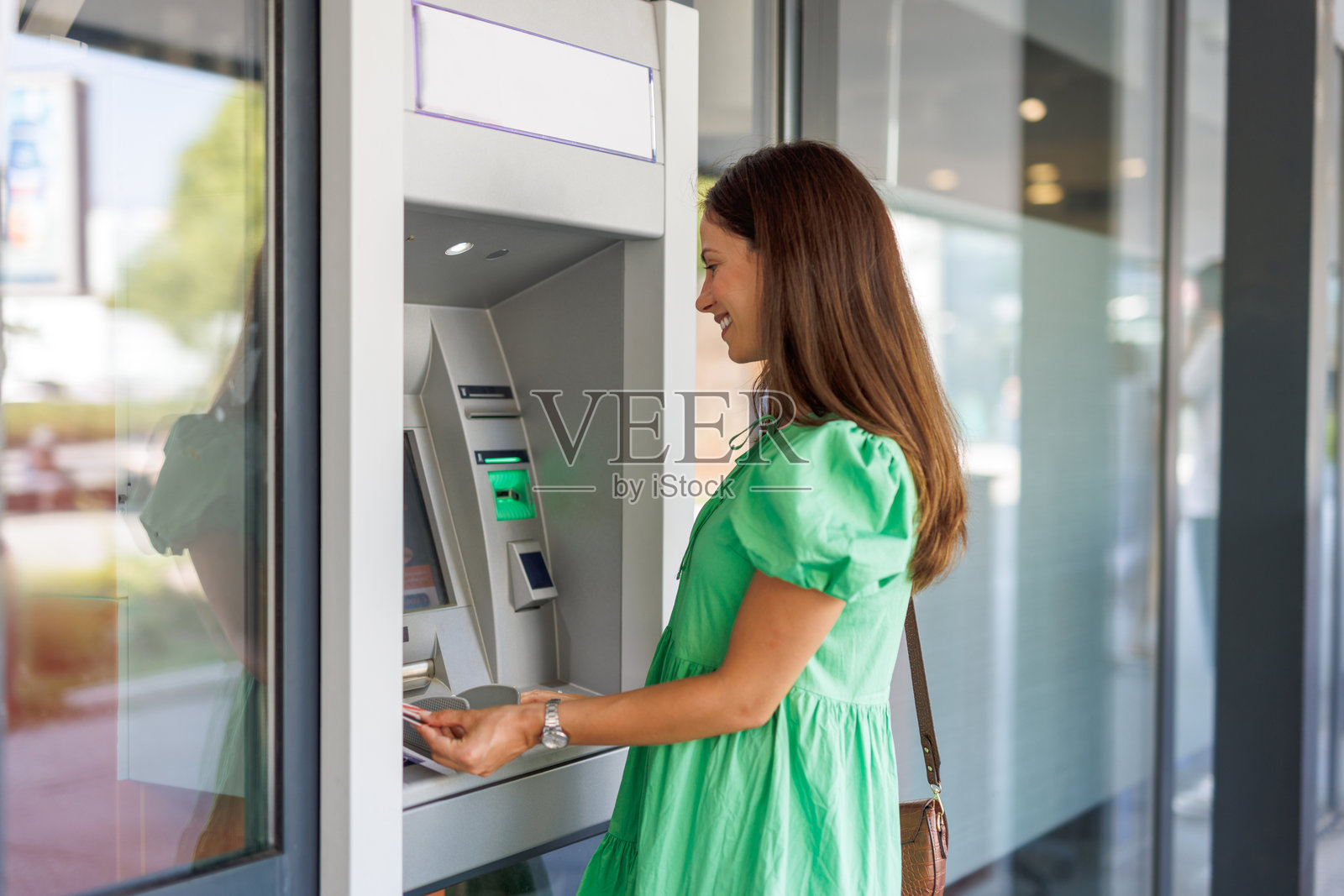 快乐的女人使用自动取款机进行交易照片摄影图片