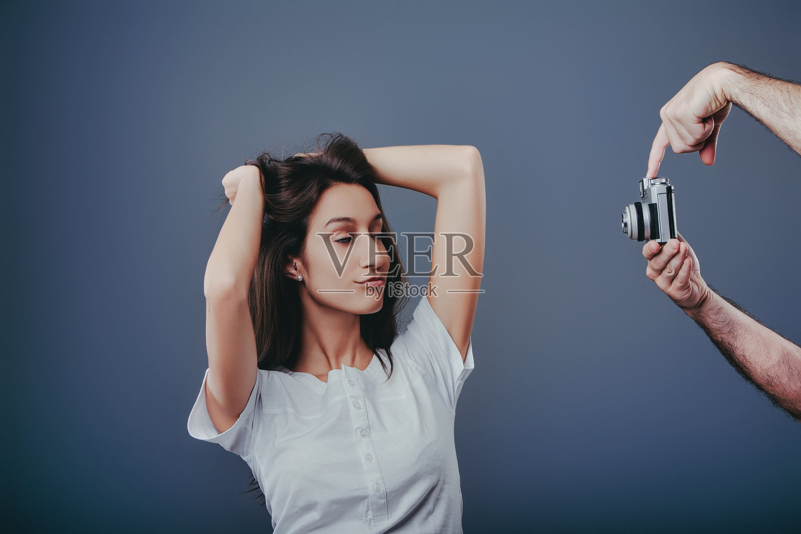 年轻女子在蓝色背景上为摄影师摆姿势照片摄影图片