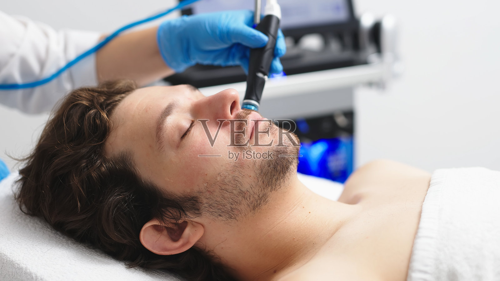 一名男子在美容诊所接受面部护理。这种先进的程序使皮肤恢复活力和活力,是在广告中展示优质护肤服务的理想选择。照片摄影图片