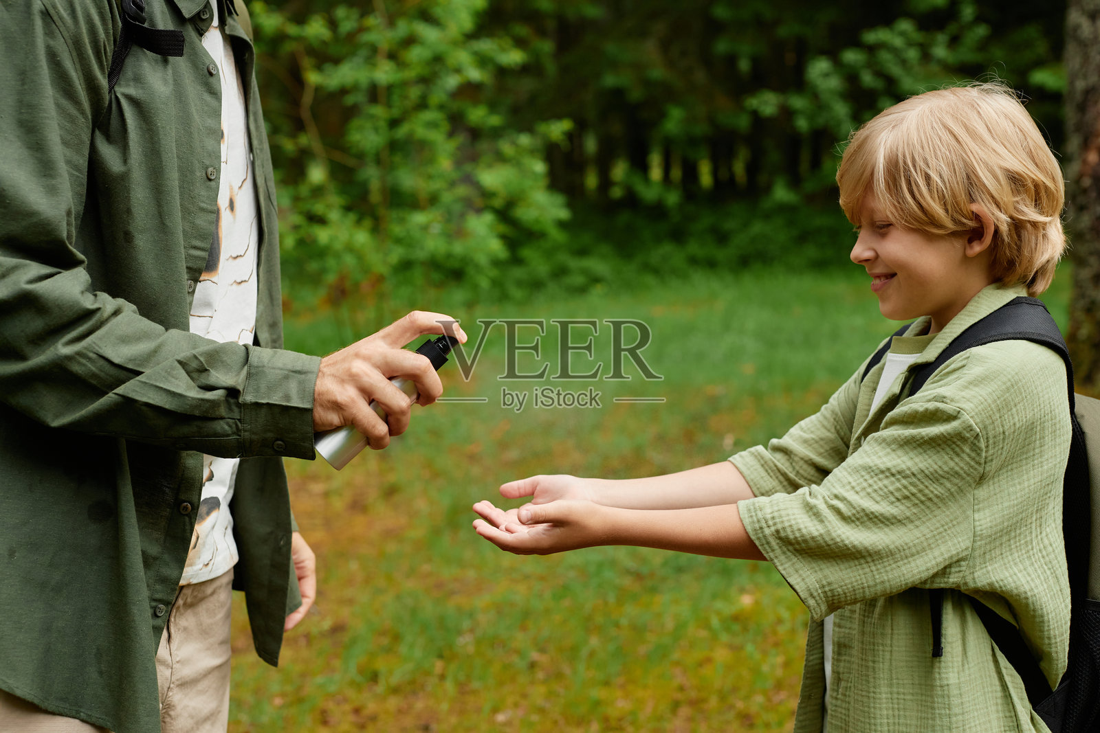 在公园里给孩子的手上喷洗手液照片摄影图片