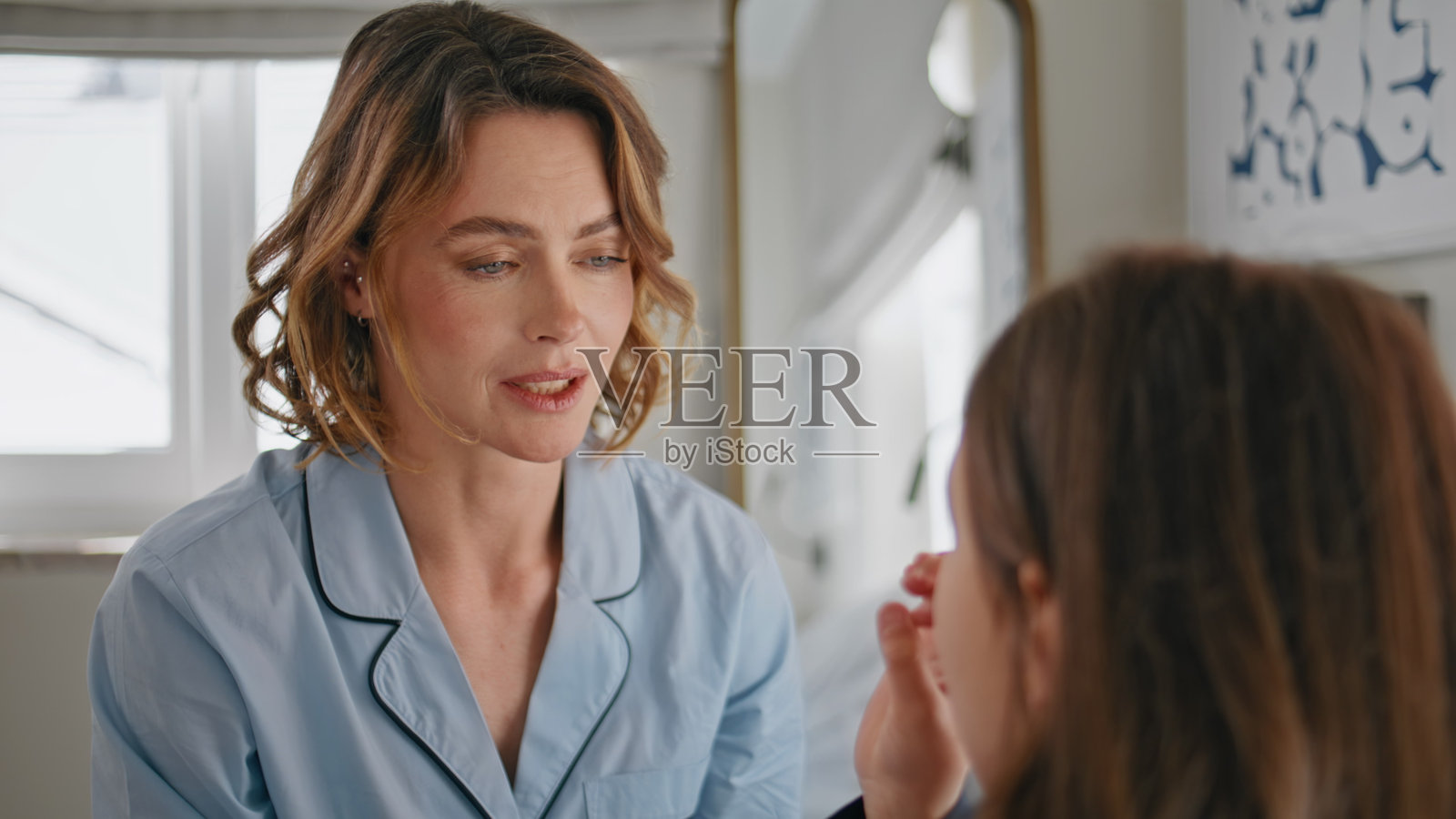 积极的母亲谈话女儿在现代卧室的特写。微笑女士睡衣照片摄影图片