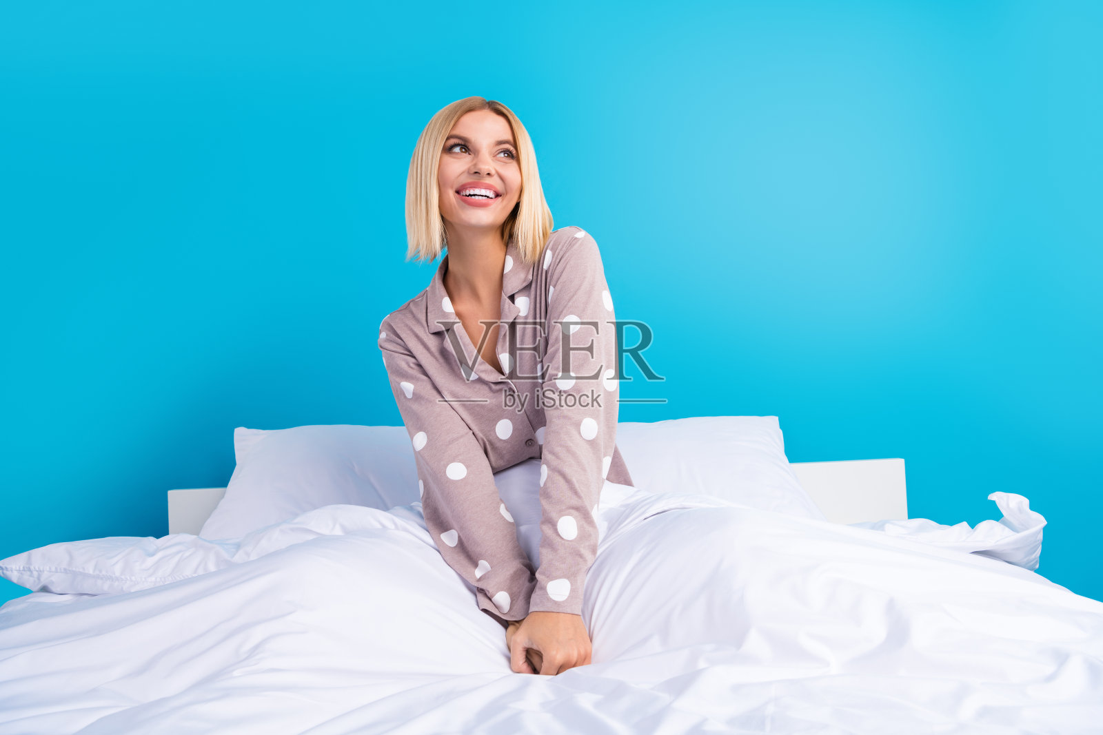 漂亮的年轻女孩的肖像床上看空的空间穿点睡衣孤立在蓝色的背景照片摄影图片