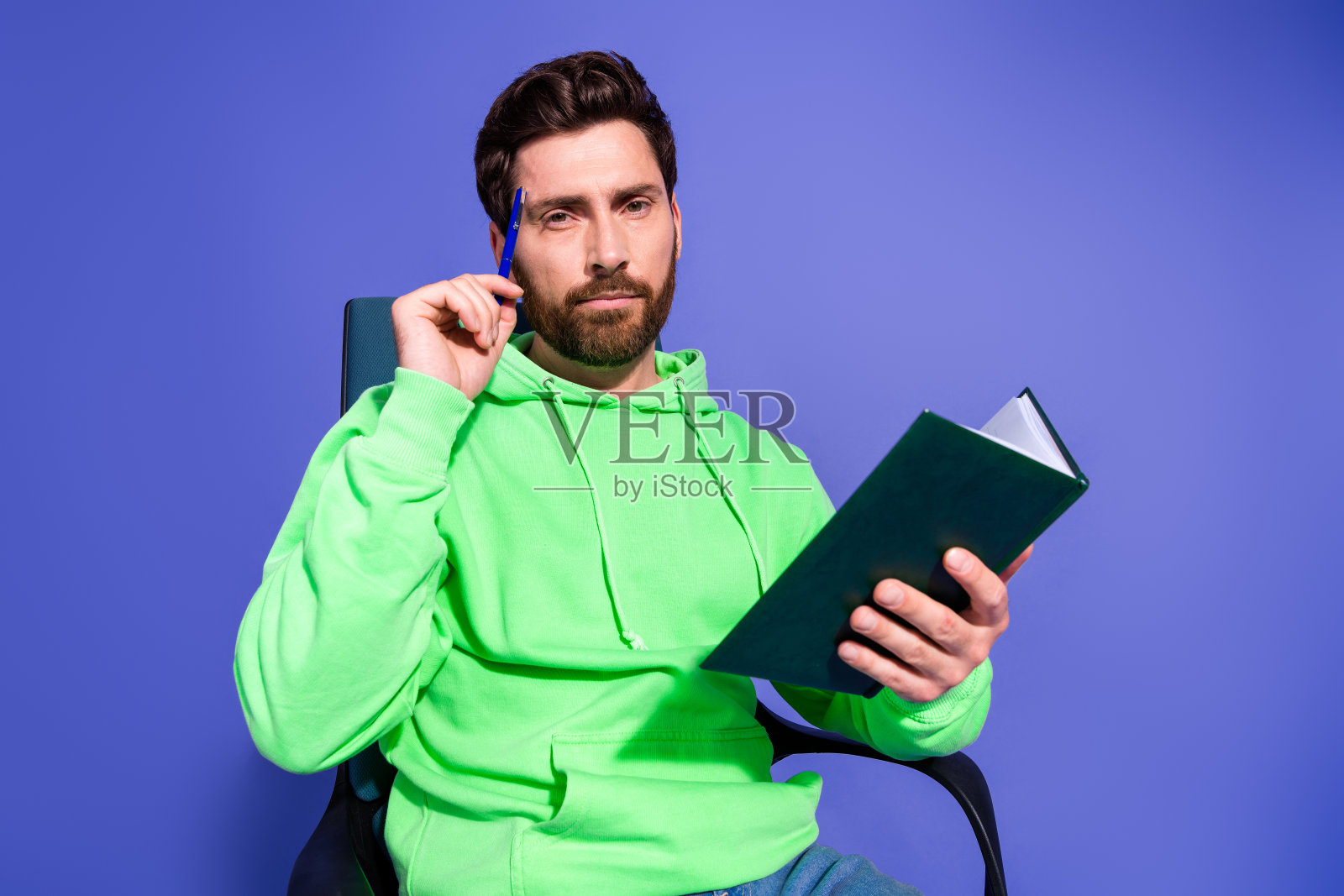 迷人的年轻人的照片肖像坐在扶手椅上笔记本思想穿着时尚的绿色衣服孤立在紫色的背景照片摄影图片