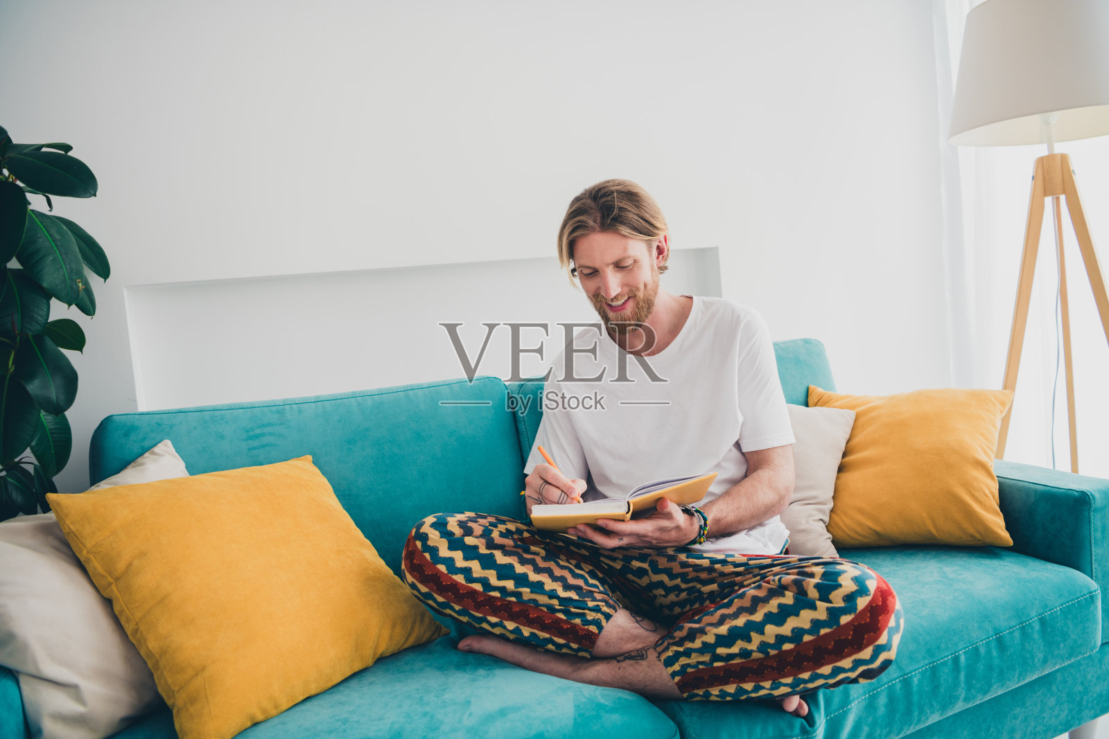 帅哥的全身照片坐在沙发上写笔记本穿着睡衣消磨时间宽敞的房子室内房间照片摄影图片