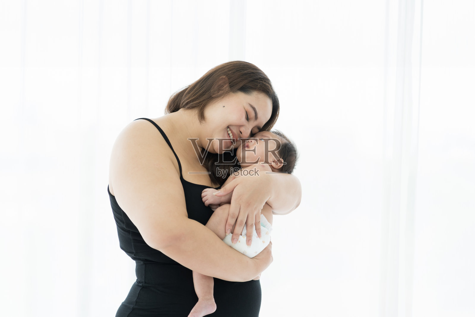 亚洲大码妈妈在家里抱着她刚出生的孩子照片摄影图片