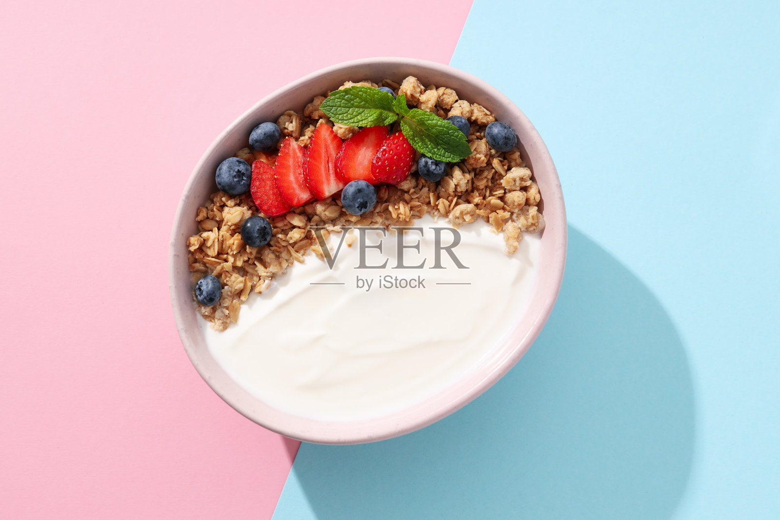 碗与酸奶和浆果在粉红色和蓝色的背景,俯视图照片摄影图片