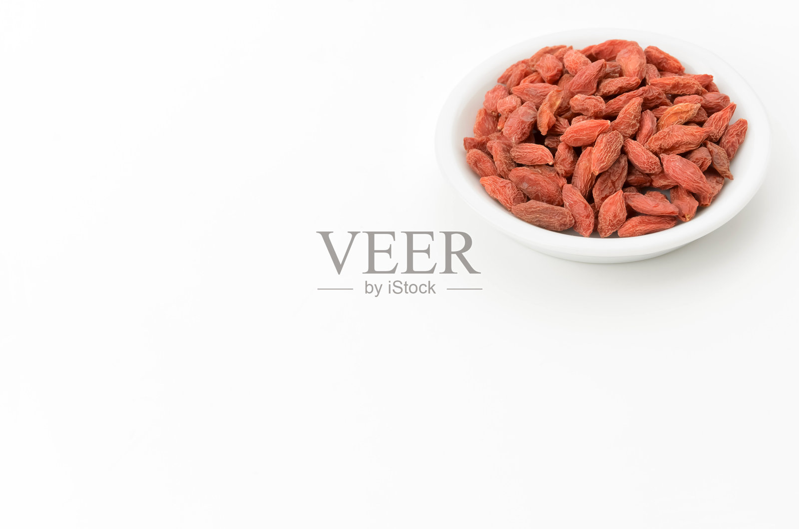 干枸杞浆果放在盘子里,背景是白色的照片摄影图片