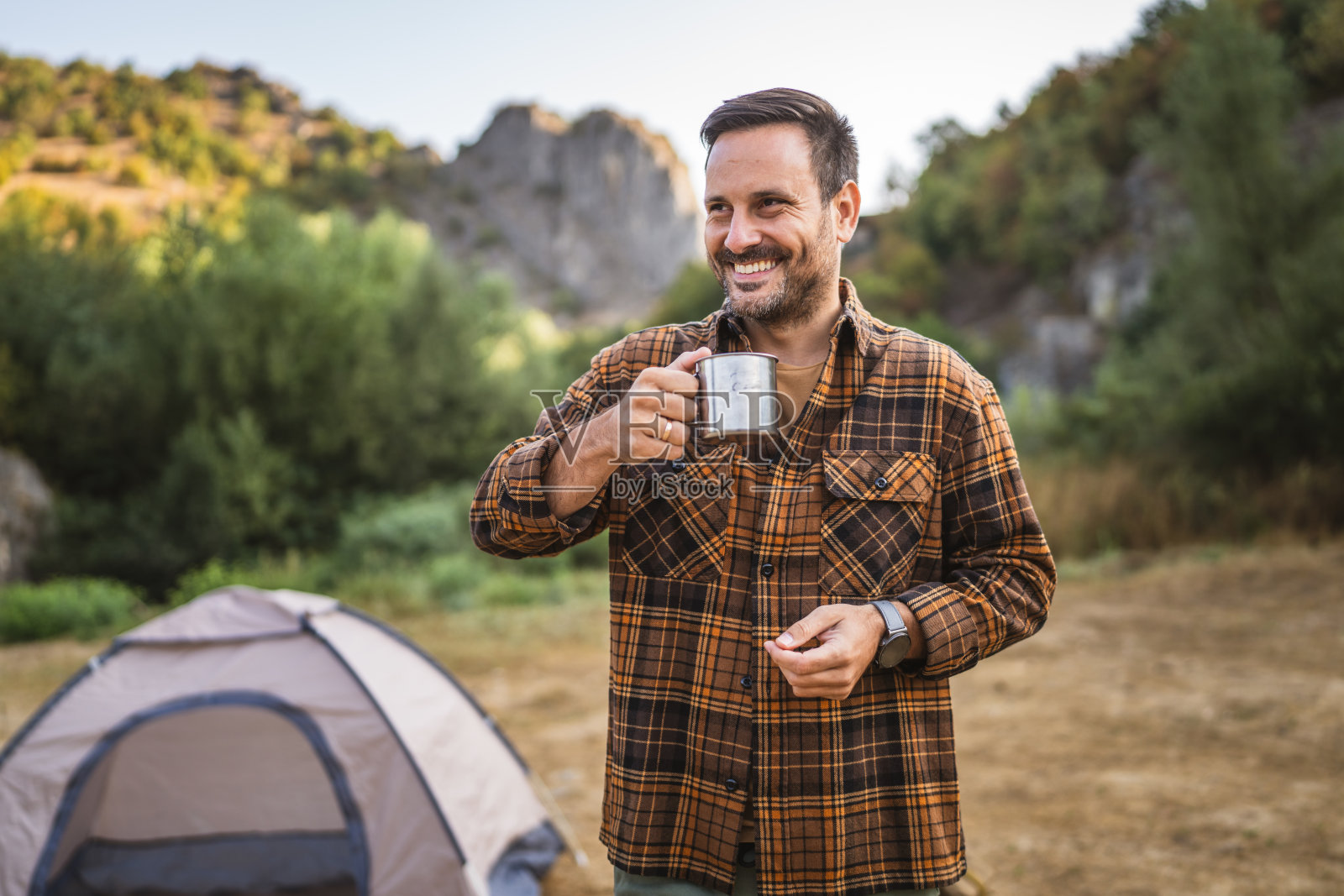成年白种人在露营时在帐篷前喝咖啡照片摄影图片
