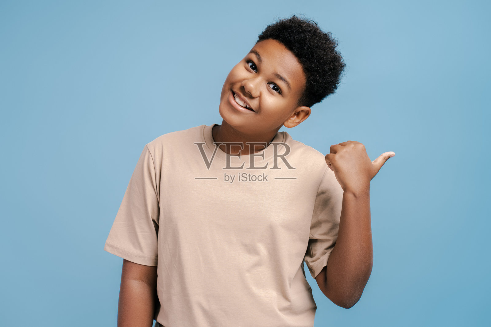 积极的非洲裔美国男孩的肖像摆姿势,用手指指着一边照片摄影图片