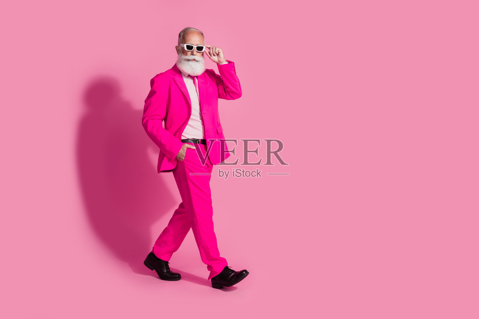严肃的老酷男人绅士男友走路的全身照片,戴着太阳镜,时尚的粉红色西装孤立在柔和的颜色背景照片摄影图片