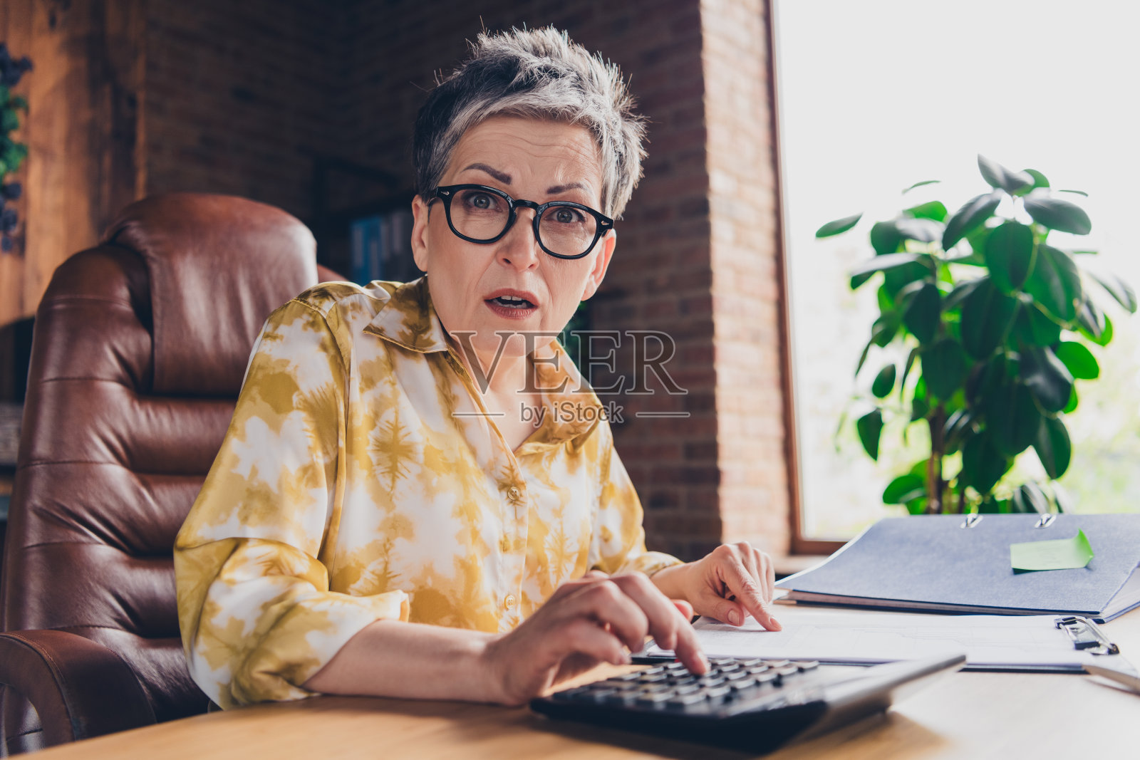 忧心忡忡的退休女簿记员在室内工作站工作区清点报告的照片照片摄影图片