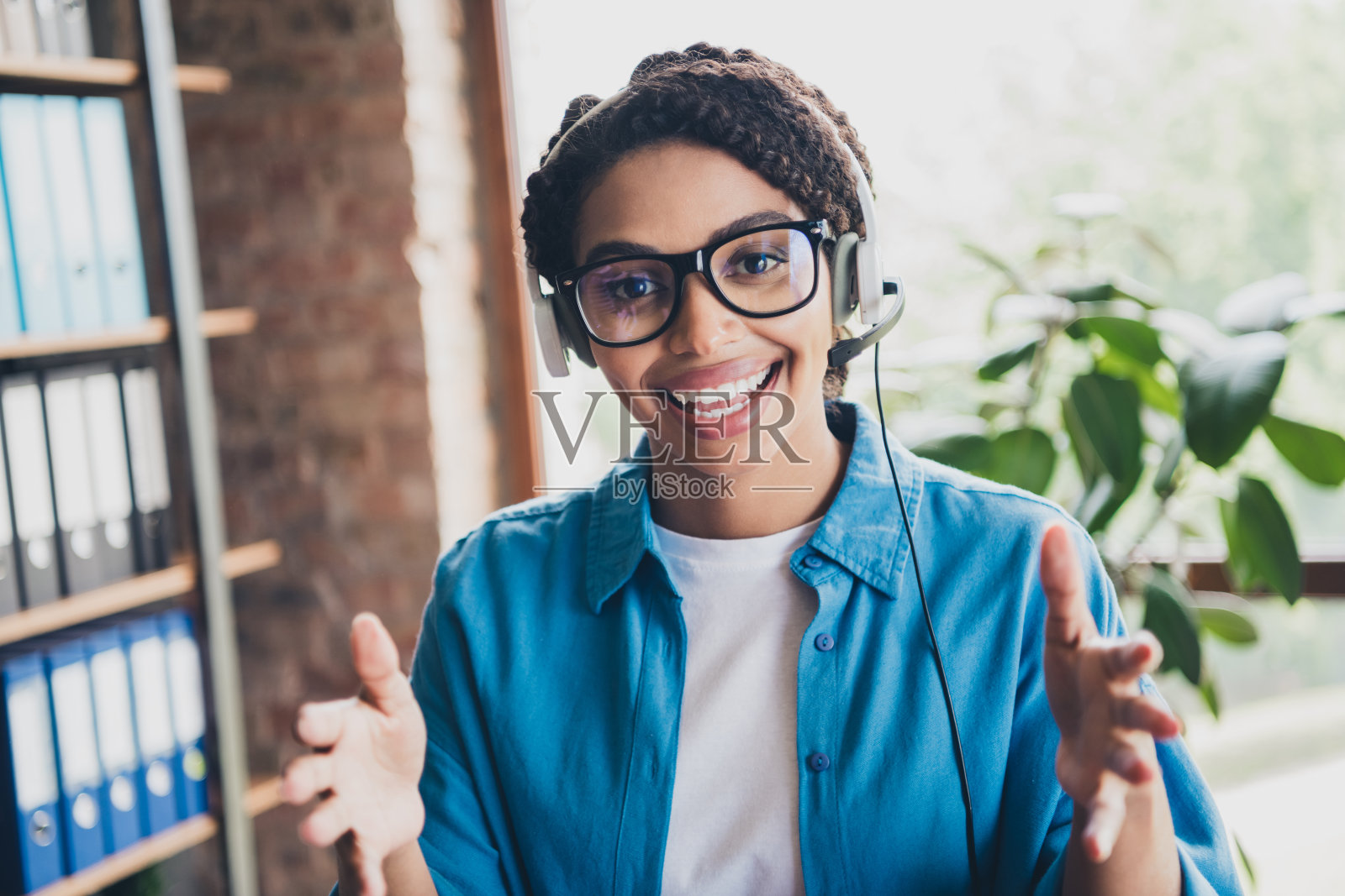 可爱的年轻女士的照片手持电话呼叫中心解释穿着蓝色衬衫舒适的程序员启动办公室阁楼房间内部照片摄影图片