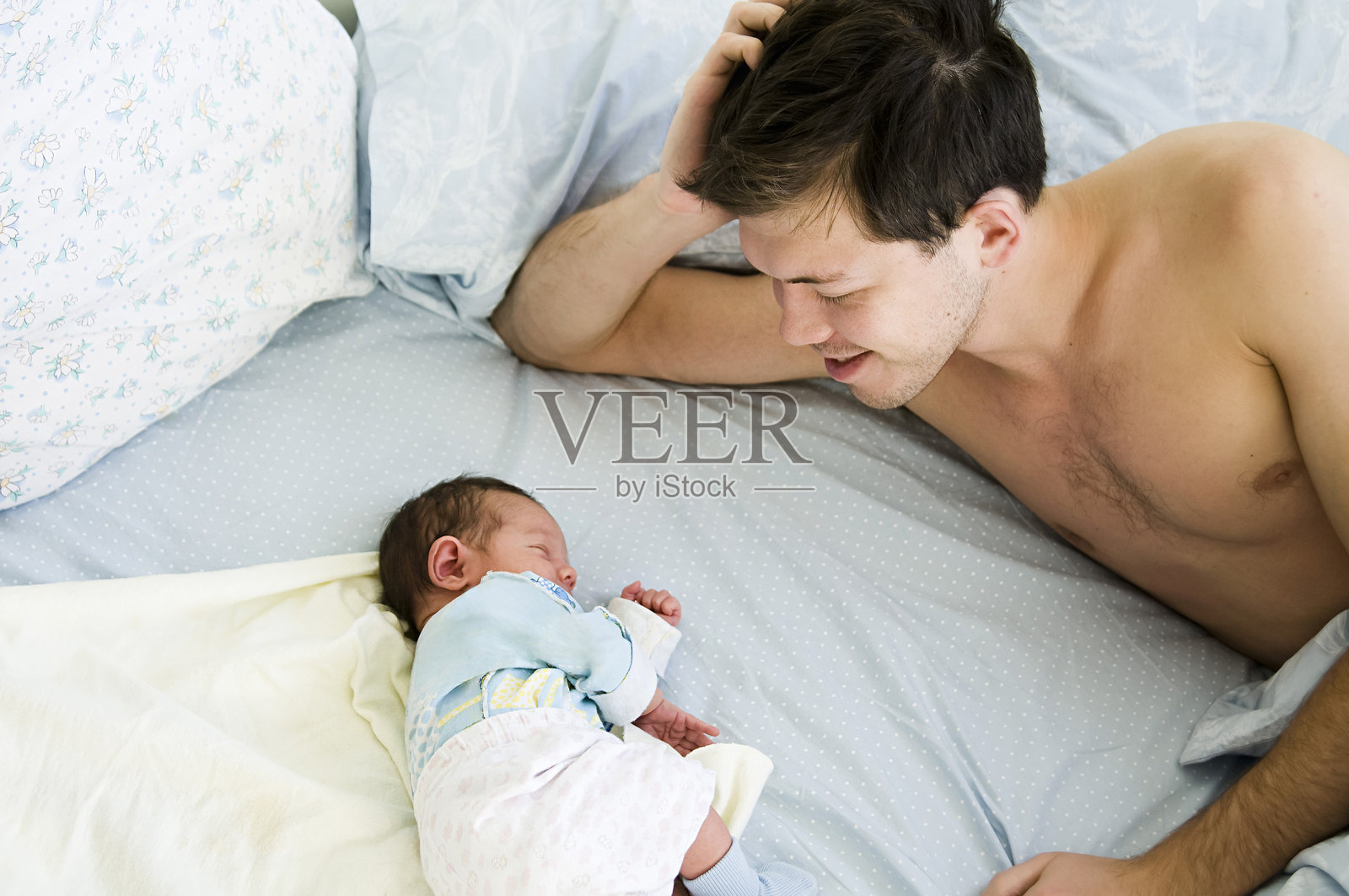 一位年轻的父亲在欣赏他刚出生的孩子。照片摄影图片