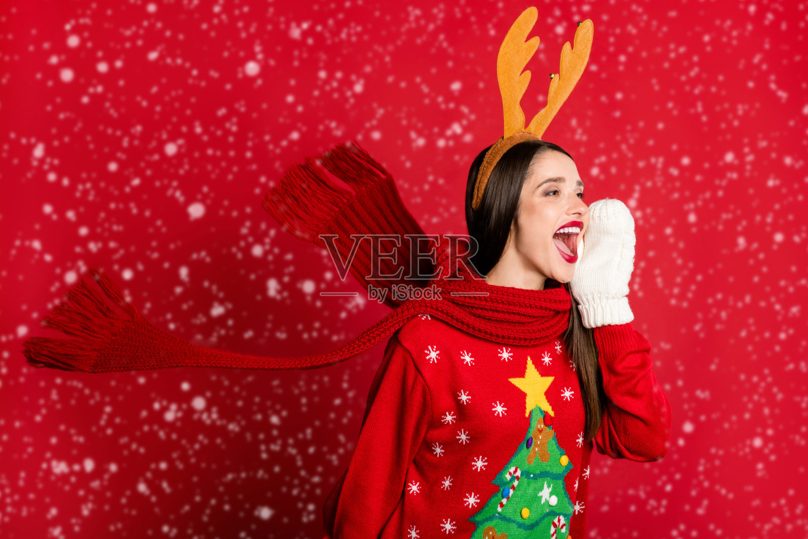 开朗的年轻女子的照片看说新闻空空间戴围巾手套鹿头带孤立的红色背景照片摄影图片