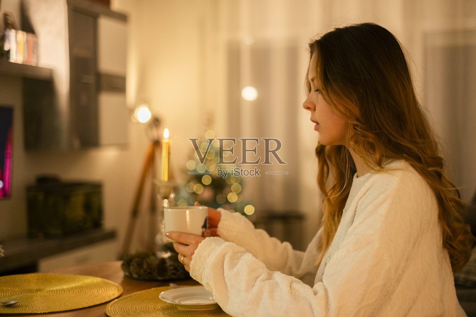 穿着白色睡衣的女孩在她家客厅喝茶照片摄影图片